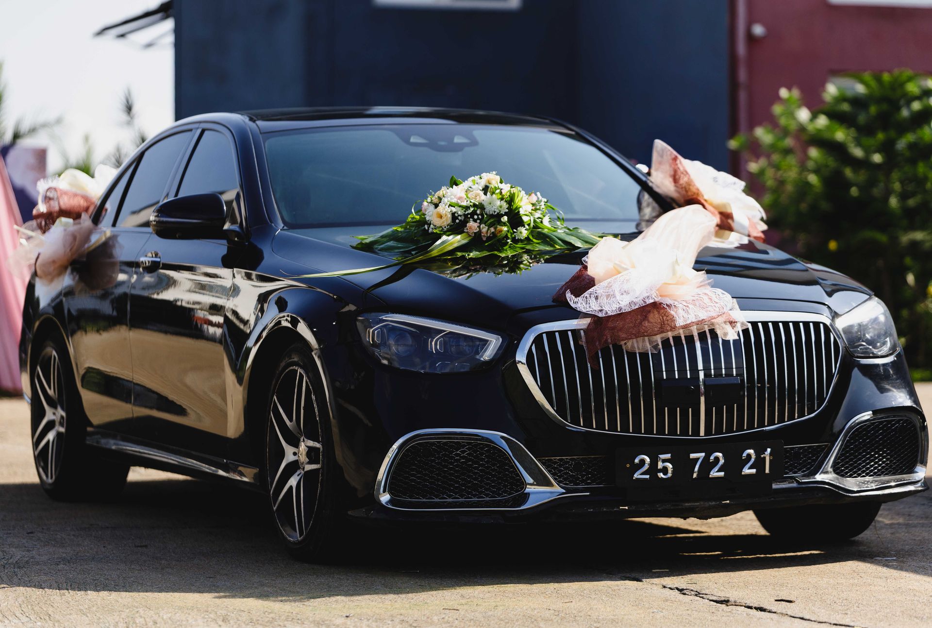 Luxurious black car decorated with flowers and ribbons, perfect for a sophisticated wedding occasion.